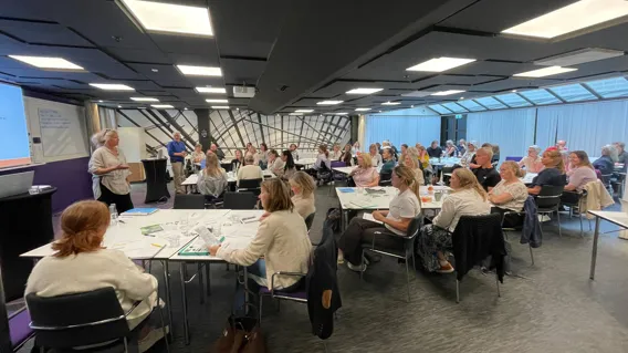 En grupp människor som sitter vid bord i ett rum.