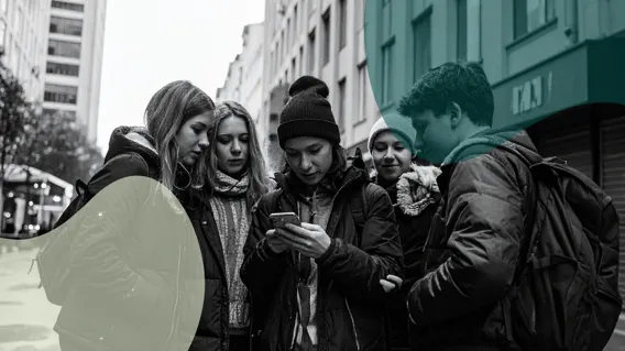 En grupp ungdomar står och tittare en mobiltelefon.