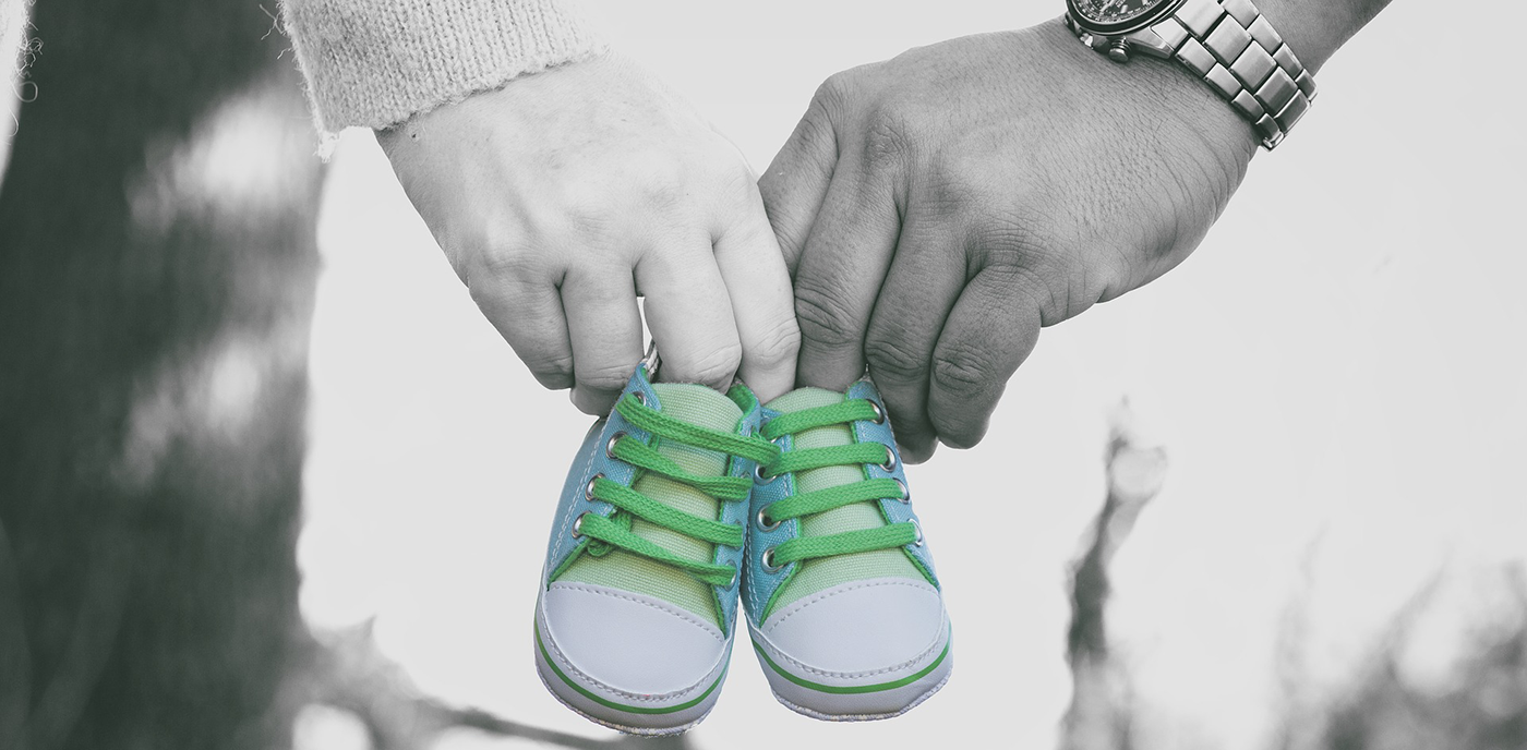 Föräldrar med det lilla barnets skor i handen