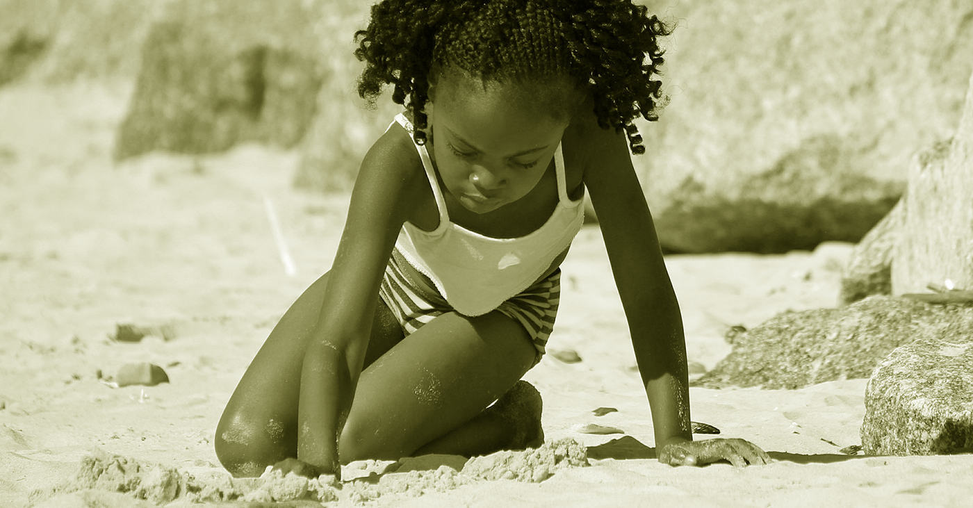 Ung svart tjej i sanden